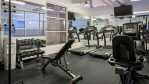 Un gimnasio con cintas de correr, mancuernas y máquinas de pesas.