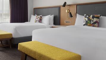 Ein Hotelzimmer mit zwei Betten, einer Bank, einem Nachttisch und einer Lampe.