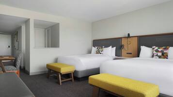 Une chambre d’hôtel avec deux lits, un bureau, une chaise et un banc.