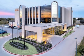 A modern building with a glass facade, a prominent entrance, and a landscaped area with a circular garden.