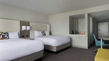 Une chambre d’hôtel avec deux lits, un bureau, une chaise et un miroir.