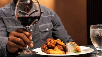 Una persona sosteniendo una copa de vino con un plato de comida frente a ella.