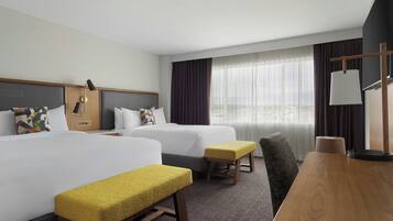 Ein Hotelzimmer mit zwei Betten, einem Holztisch, einem Stuhl und einem kleinen Tisch.