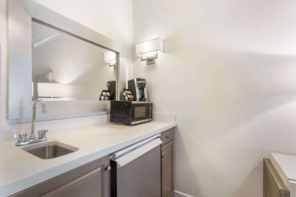Une salle de bain moderne équipée d’un lavabo, d’un miroir, d’un four à micro-ondes et d’une machine à café.