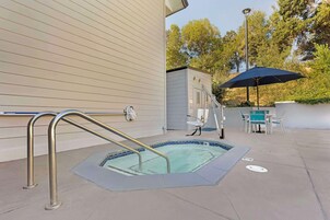 A swimming pool with a metal ladder, a covered seating area, and a small building in the background.