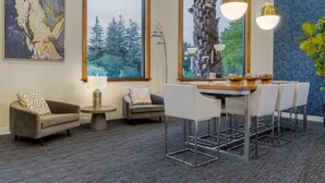 A modern living room with a dining area, large windows, and a view of trees. - Best Western Plus Novato Oaks Inn (Novato)