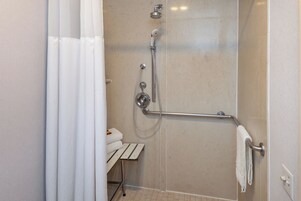 Un área de ducha con barra de apoyo, perchero y cabezal de ducha.