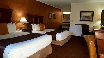 A hotel room with two beds, a desk, a chair, and a television.