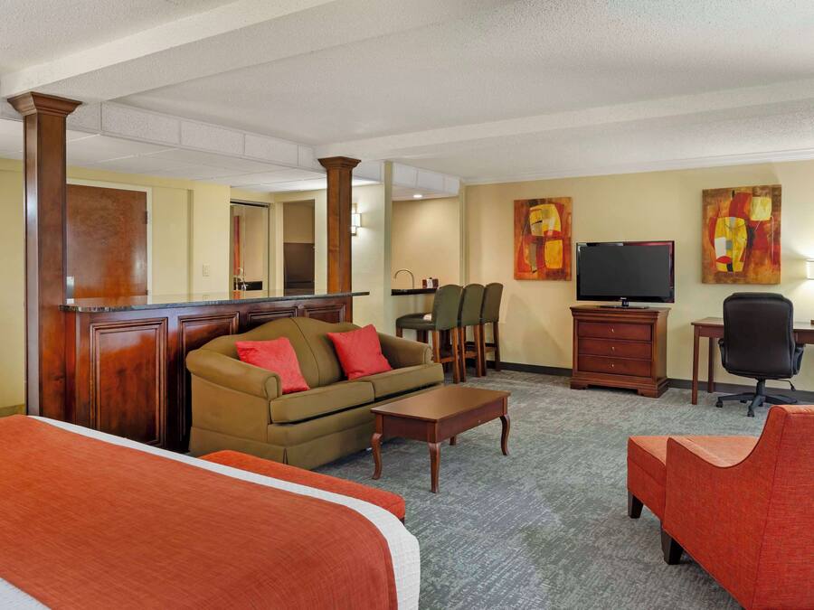 Habitación de hotel con cama, sofá, escritorio, televisor y obras de arte en las paredes.