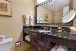 A bathroom with a marble countertop, a sink, a mirror, and towels.