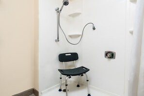 A bathroom with a shower, a black chair with wheels, and a white door. - Super 8 by Wyndham Rochester Mayo Clinic Area (Rochester)