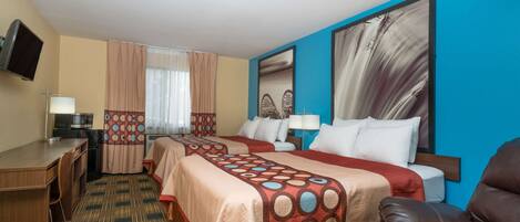 Habitación de hotel con dos camas, un escritorio, un televisor y un ventanal con cortinas.