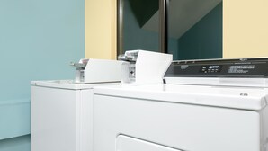 A front-loading white washer and dryer in a laundry room with a window and a door. - Super 8 by Wyndham Rochester Mayo Clinic Area (Rochester)