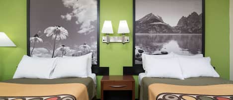 Habitación de hotel con dos camas, paredes verdes, dos cuadros enmarcados, una mesita de noche con lámparas y una colcha estampada.