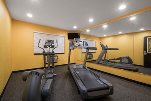 Un gimnasio con cintas de correr, elíptica y bicicleta estática.