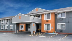 A multi-story hotel with a grey and orange facade, a covered entrance, and a parking lot with marked spaces. - Super 8 by Wyndham Rochester Mayo Clinic Area (Rochester)