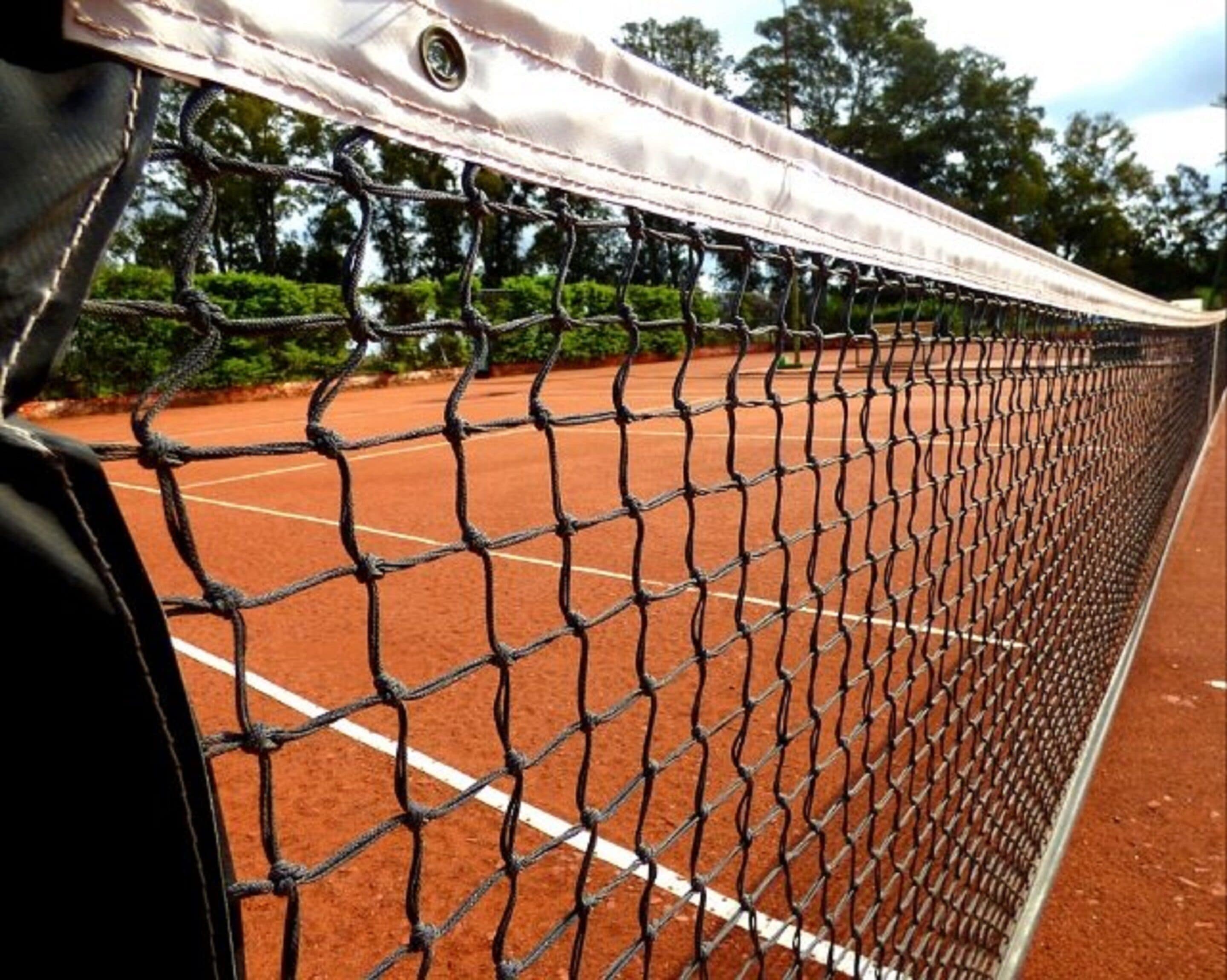 A tennis court with a net in the foreground.
