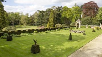 A well-manicured garden with a central lawn, neatly trimmed hedges, and a small gazebo.