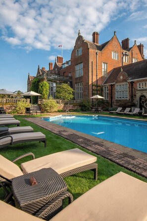A pool area with lounge chairs and a brick building in the background.