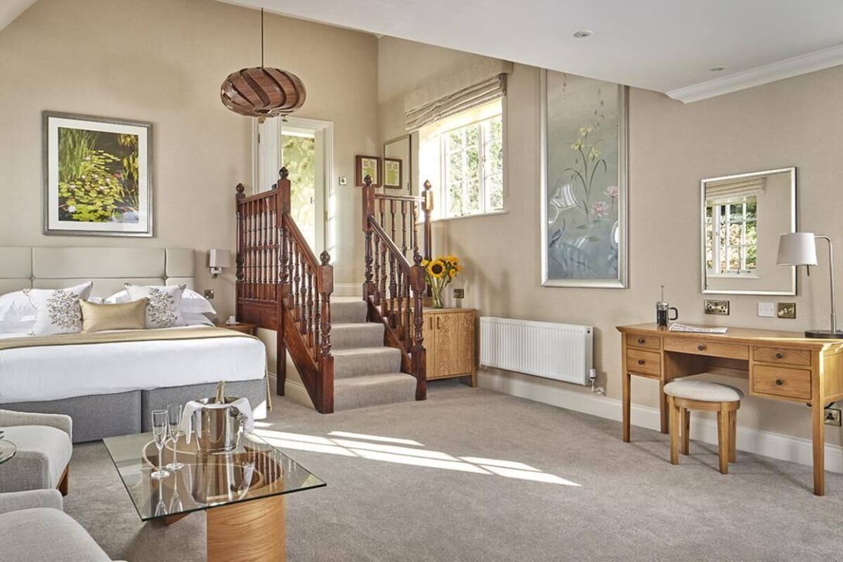 A bedroom with a bed, a desk, a chair, a staircase, and a window.