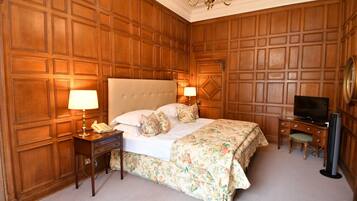 Ein Hotelzimmer mit einem großen Bett, Holzwandverkleidung, einem Schreibtisch mit Fernseher und einem Sessel.