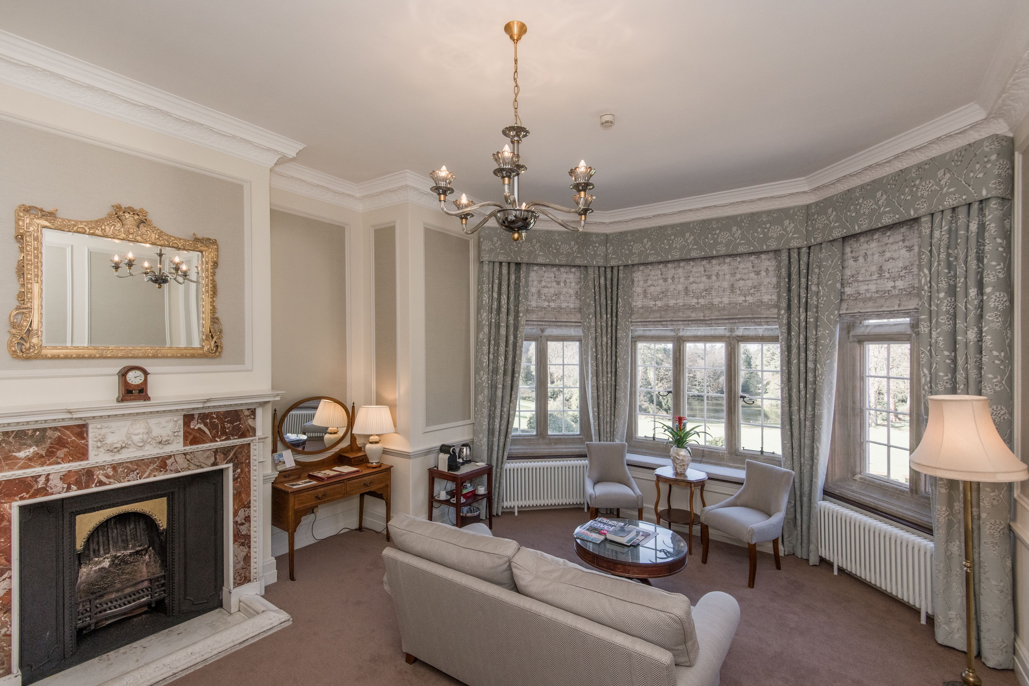 A well-appointed living room with a fireplace, a chandelier, a sofa, and two armchairs.