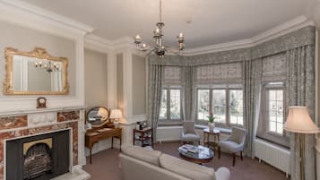 A well-appointed living room with a fireplace, a chandelier, a sofa, and two armchairs.