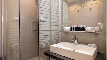 Une salle de bain moderne avec une douche à parois de verre, un lavabo blanc et un meuble-lavabo avec un miroir.