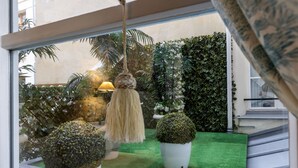 A view of a room with a green artificial turf floor, a hanging lamp, and potted plants.