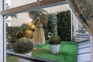 Vista de una habitación con suelo de césped artificial verde, una lámpara colgante y plantas en macetas.