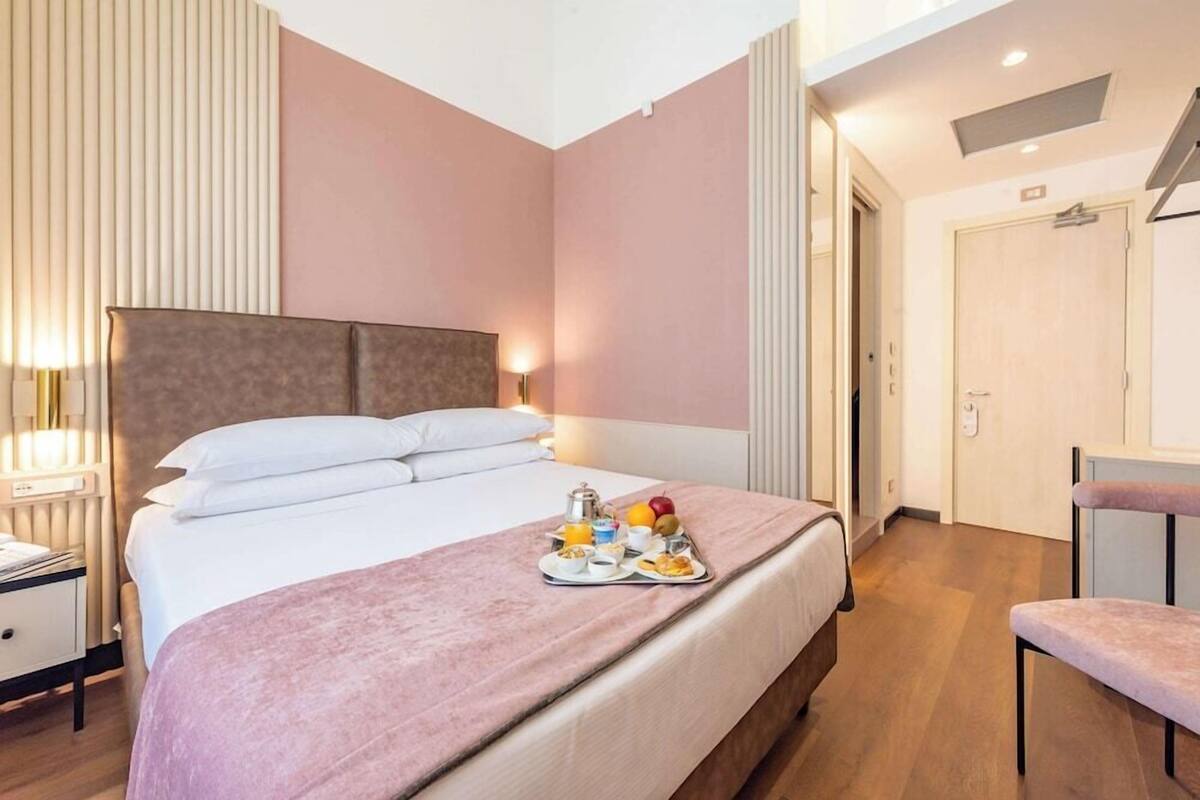 Une chambre d’hôtel moderne avec un grand lit, une table de chevet et une chaise.
