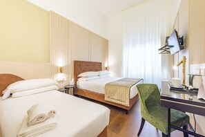 Een hotelkamer met twee bedden, een bureau met stoel, een televisie en een raam met gordijnen.