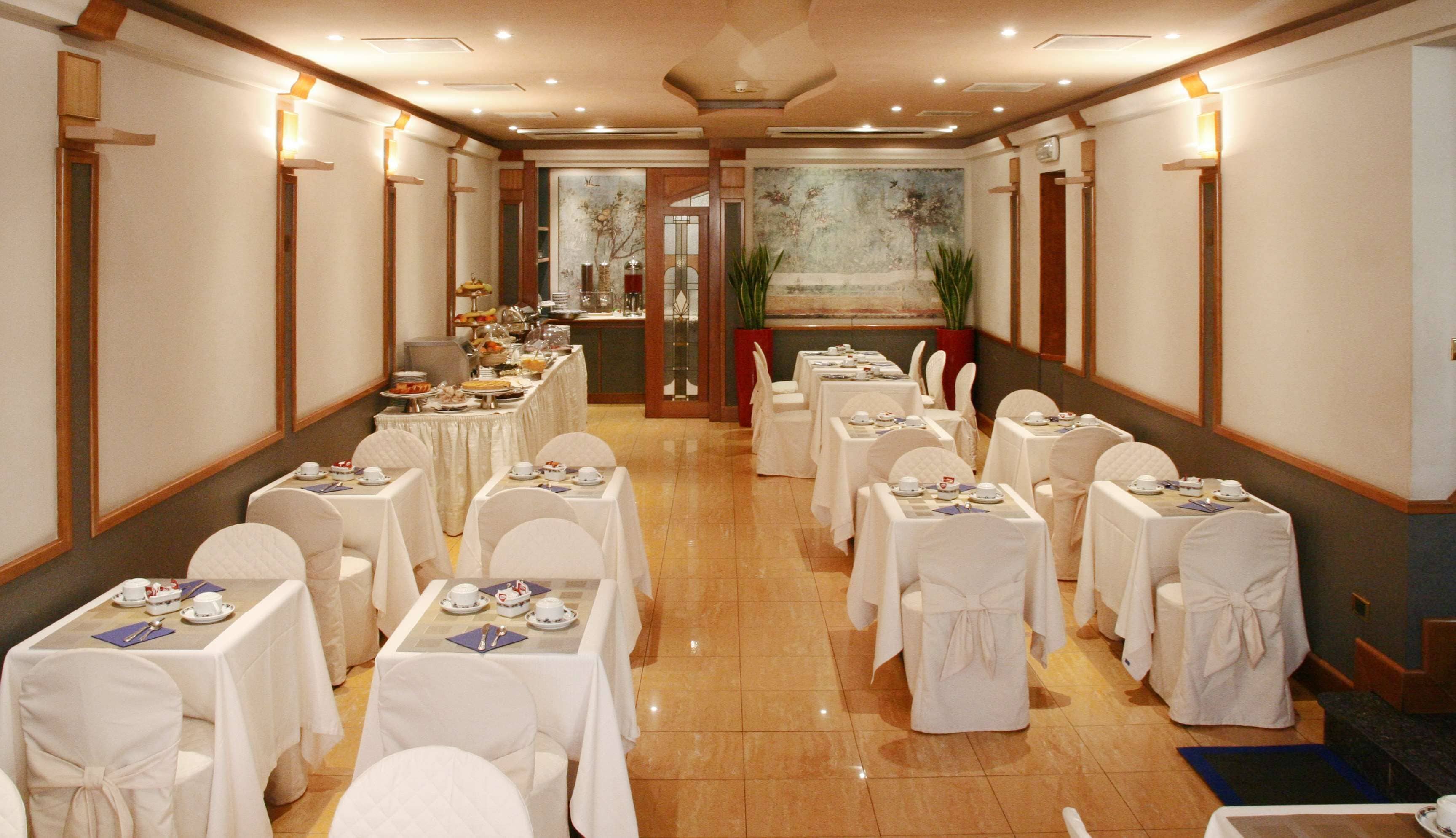Un salón de banquetes con mesas dispuestas para un evento formal, que incluye un bufé central y un cuadro grande en la pared de fondo.
