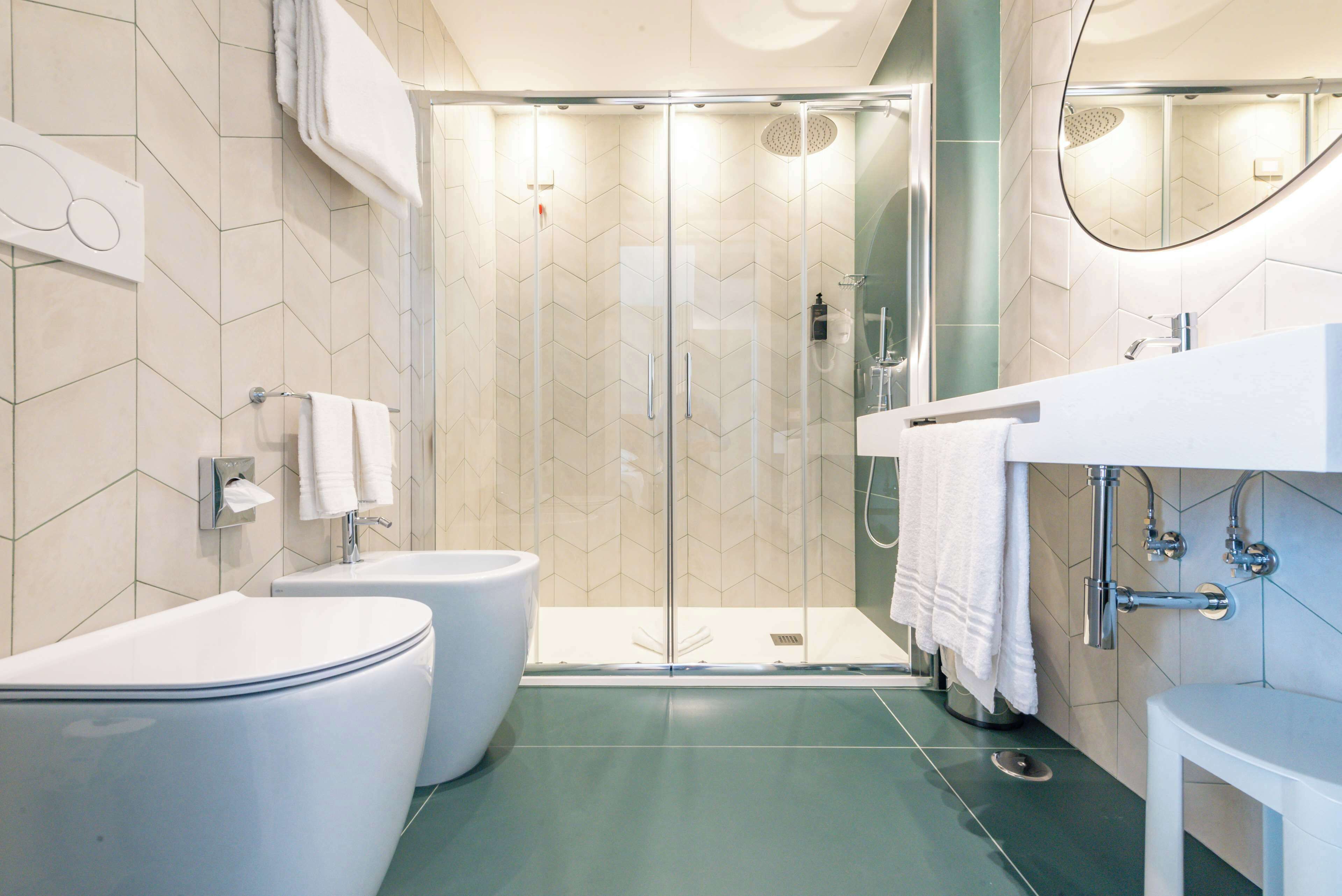 Un baño moderno con ducha envuelta en vidrio, un inodoro blanco y un lavabo blanco con un espejo encima.