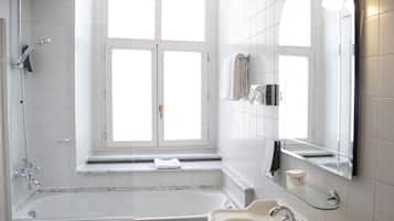 Un bagno moderno con una vasca, un lavandino, uno scaffale in vetro e un'ampia finestra.