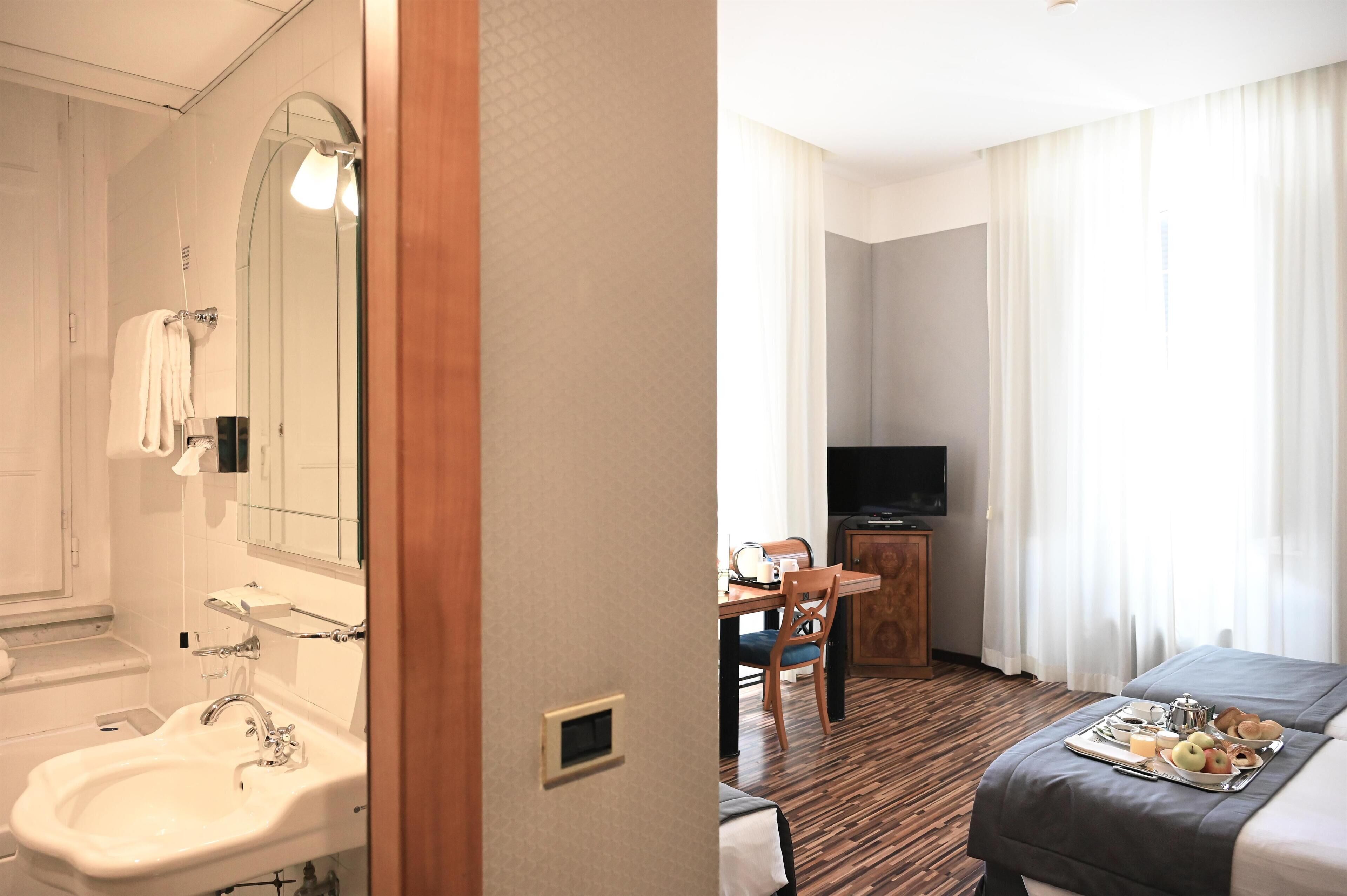 A hotel room with a bathroom, a dining area, and a bed.