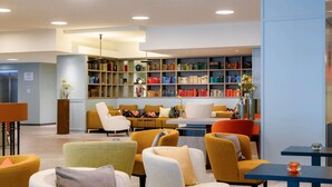 A modern library with bookshelves, comfortable seating, and a lift sign.