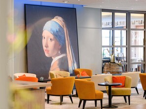 A modern interior with a large painting, orange chairs, and a wooden barrel.