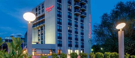 A high-rise hotel with a prominent 'Mercure' sign, multiple balconies, and a paved courtyard.