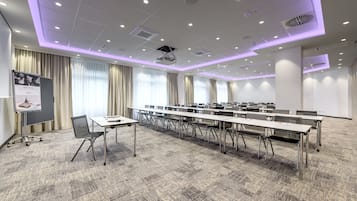 A conference room with a long table, chairs, a projector, and a whiteboard.