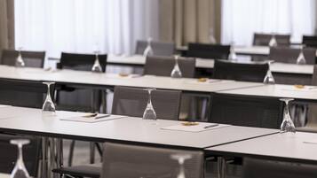 A conference room with rows of tables, chairs, and empty wine glasses.