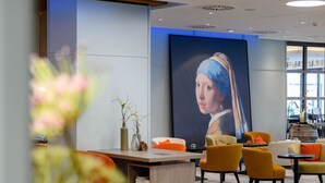 A modern lobby with a large painting, comfortable seating, and a reception desk.