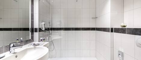 Un baño moderno con un espejo grande, dos lavamanos, ducha y retrete.