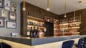 A bar area with a counter, bar stools, and shelves of bottles.