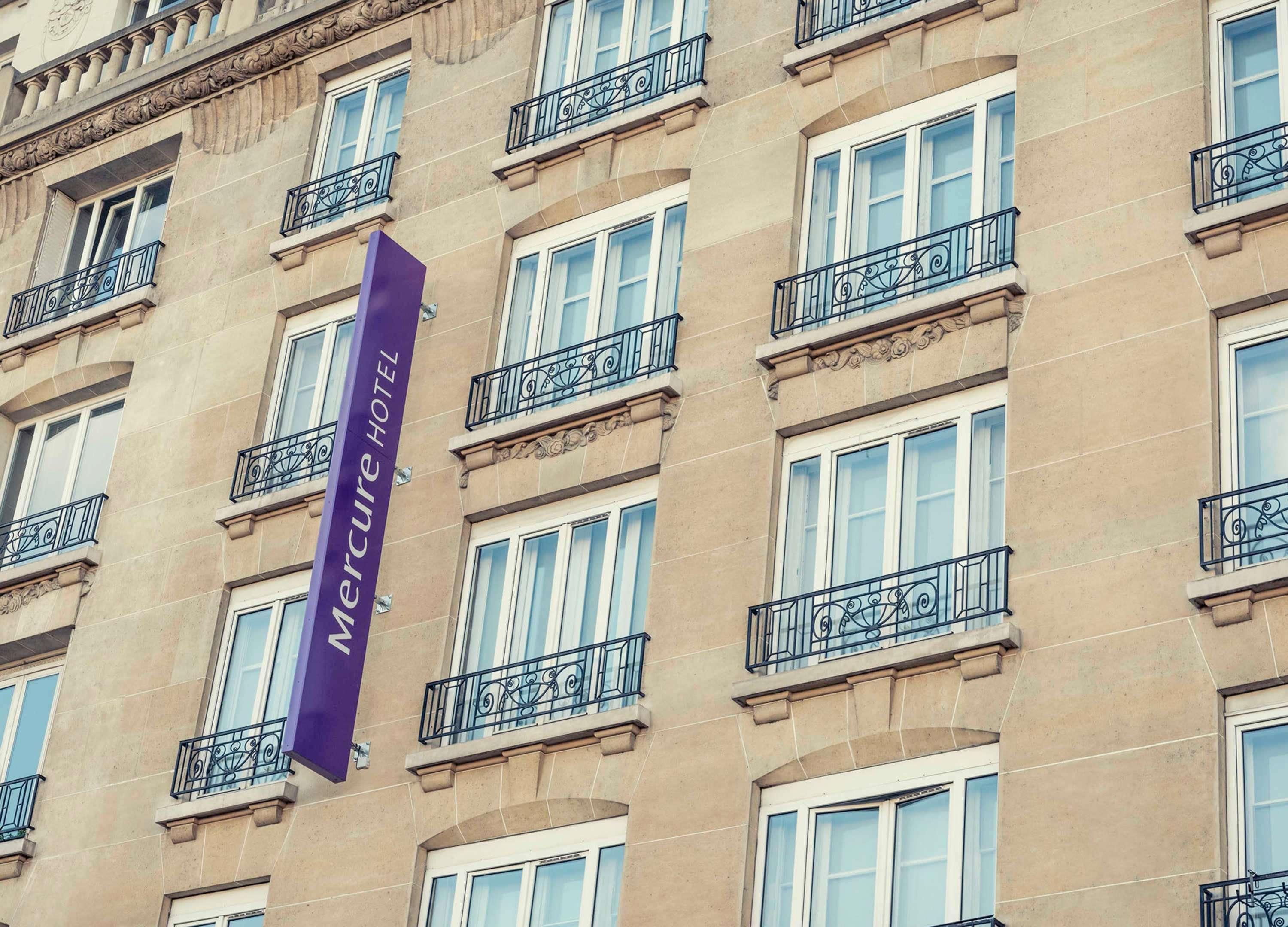 Un edificio con varias ventanas y balcones, que presenta un letrero morado destacado que dice "Mercure Hotel".