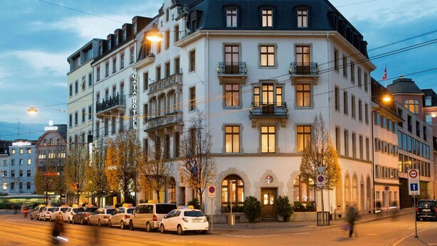 A multi-story hotel with a classic European architectural style, featuring a prominent corner entrance and multiple balconies. - GAIA Hotel Basel - the sustainable hotel (Basel)