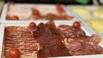 Una exhibición de diversos embutidos, incluyendo jamón en rodajas y salami, con tomates cherry y queso.
