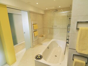 A modern bathroom with a bathtub, shower, and a towel rack.