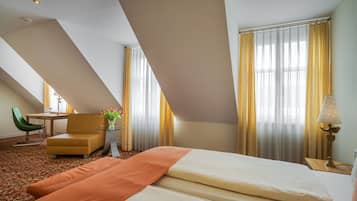 Una habitación de hotel con una cama, un escritorio, una silla y una lámpara.