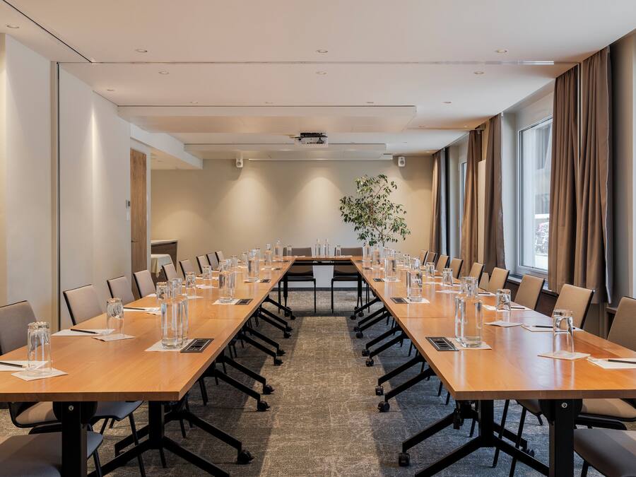Un salón de conferencias con una larga mesa, sillas y vasos de agua.